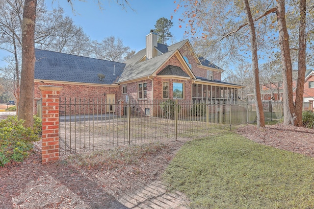 back of property with a lawn and a sunroom