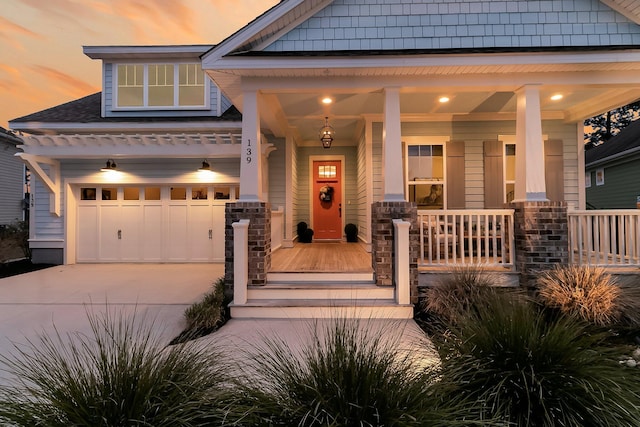 exterior entry at dusk featuring a garage and covered porch