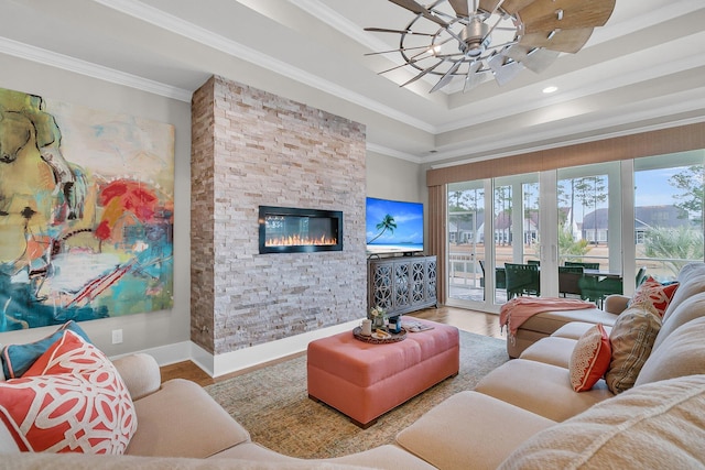 living room with ornamental molding, wood-type flooring, a fireplace, and a tray ceiling