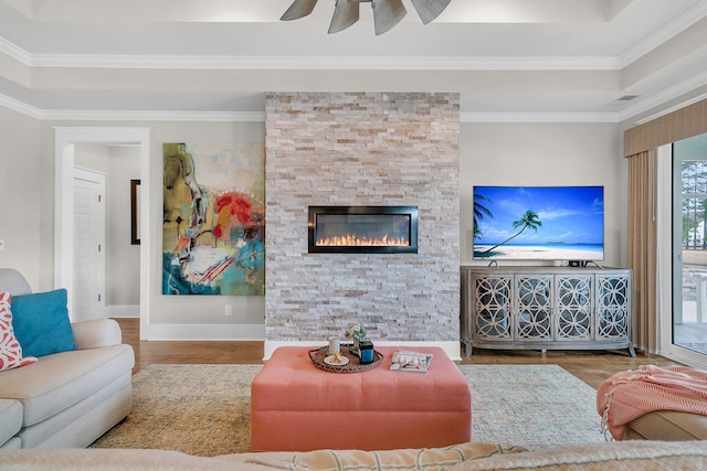 living room featuring a raised ceiling, ornamental molding, and wood-type flooring