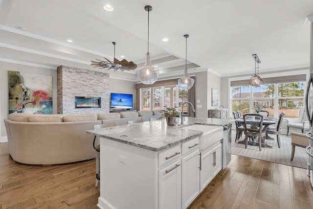 kitchen featuring sink, light stone countertops, white cabinets, a center island with sink, and stainless steel dishwasher