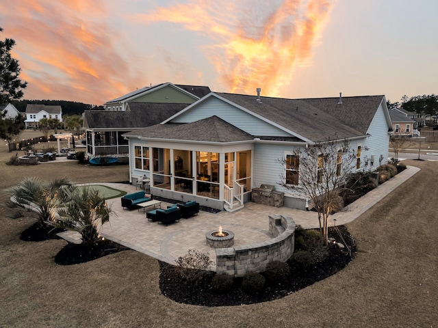 back house at dusk with a patio, a yard, a sunroom, and an outdoor living space with a fire pit