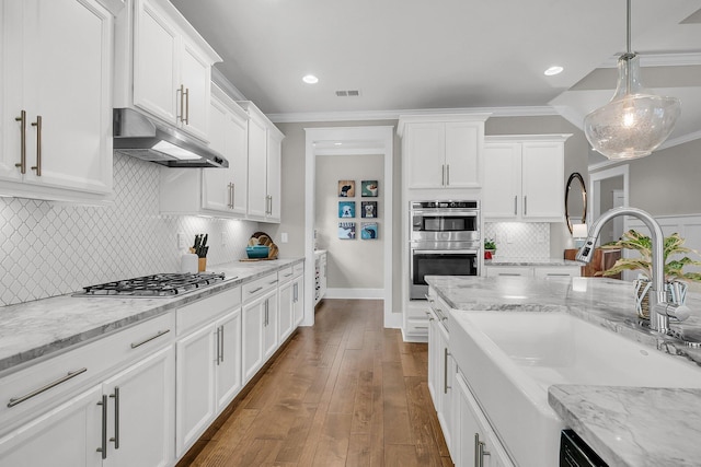 kitchen with pendant lighting, appliances with stainless steel finishes, sink, and white cabinets