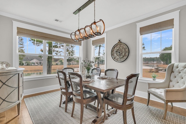 dining room featuring a healthy amount of sunlight, ornamental molding, a chandelier, and light wood-type flooring