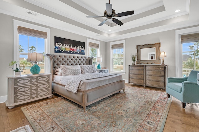 bedroom featuring crown molding, a tray ceiling, and light hardwood / wood-style floors