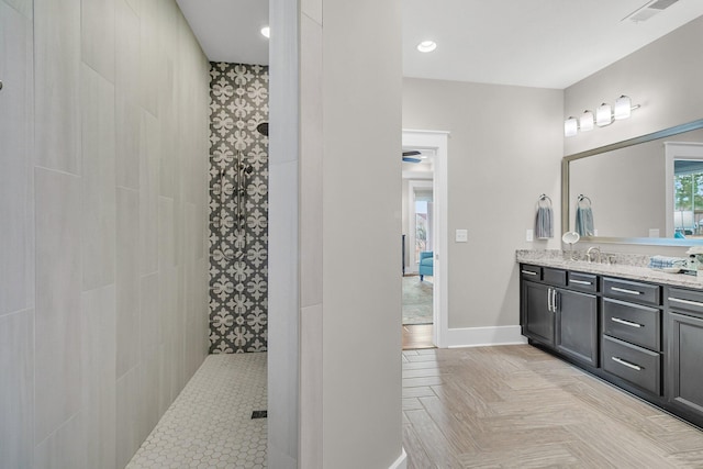 bathroom with parquet flooring, vanity, and tiled shower