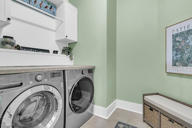 laundry room with light tile patterned flooring, cabinets, and washing machine and clothes dryer