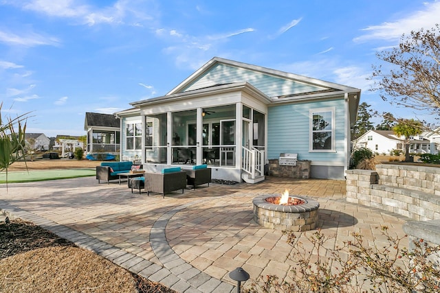 back of property featuring a patio, a sunroom, and an outdoor living space with a fire pit