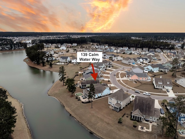 aerial view at dusk featuring a water view and a view of the beach