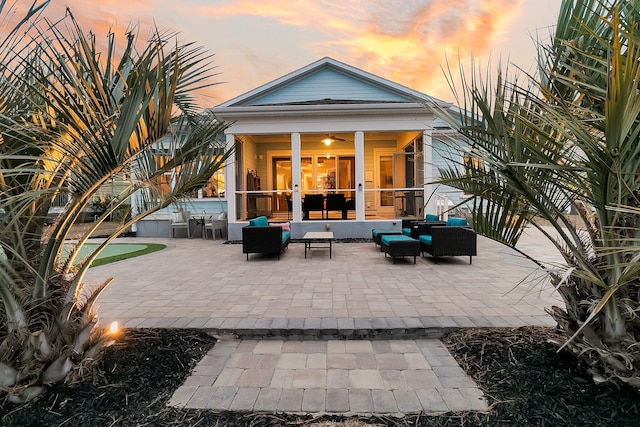 back house at dusk with a patio area, outdoor lounge area, and a sunroom