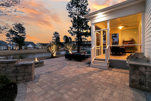 patio terrace at dusk featuring an outdoor kitchen and a fire pit