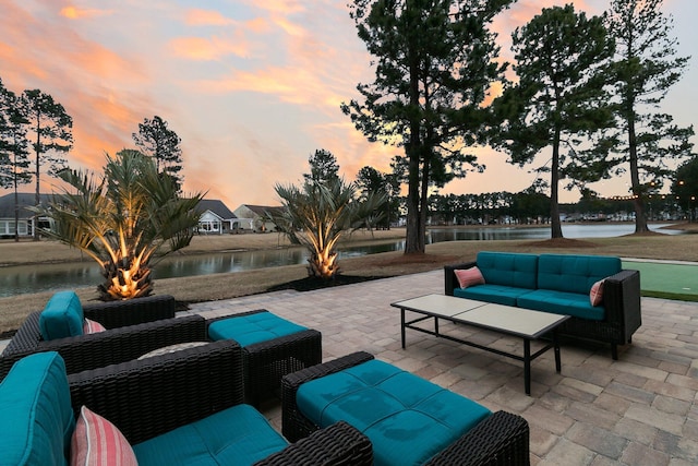 patio terrace at dusk featuring a water view and outdoor lounge area