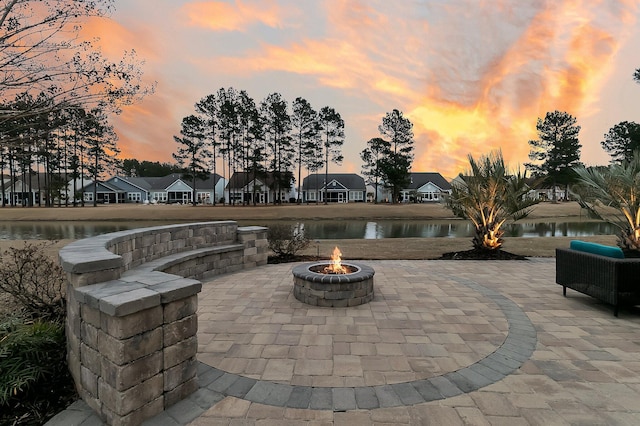 patio terrace at dusk featuring a fire pit and a water view