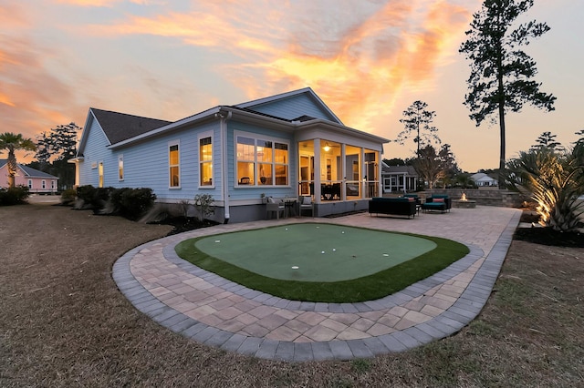 back house at dusk featuring a patio and a sunroom