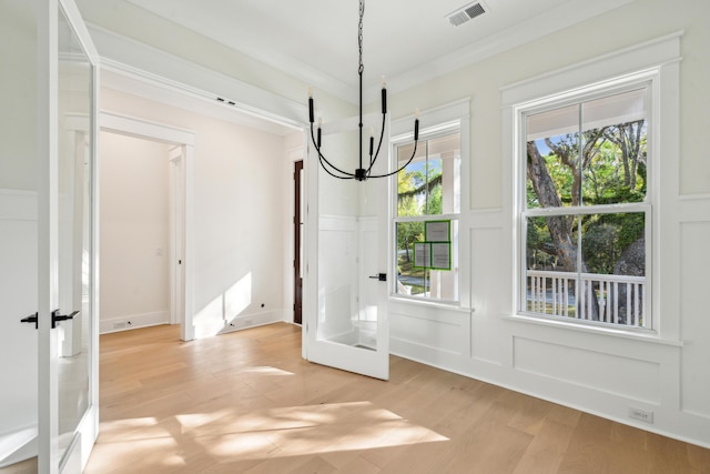 2790 Burden Creek Rd, Johns Island, SC 29455 - unfurnished dining area featuring a chandelier, a decorative wall, light wood-style floors, wainscoting, and french doors