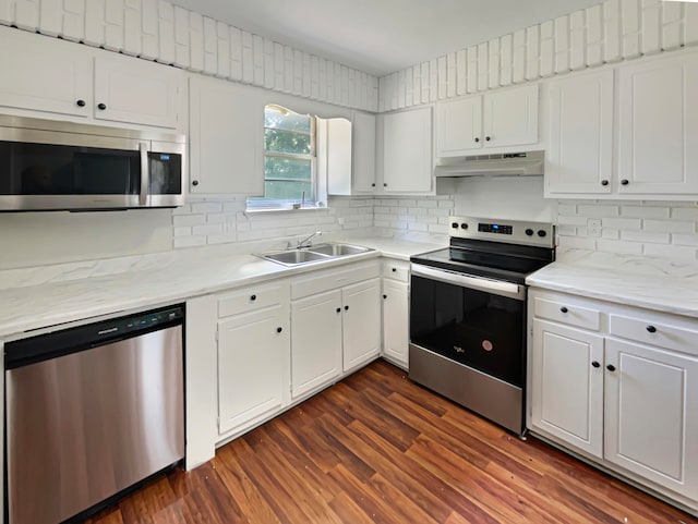 kitchen with appliances with stainless steel finishes, dark hardwood / wood-style flooring, tasteful backsplash, sink, and white cabinets