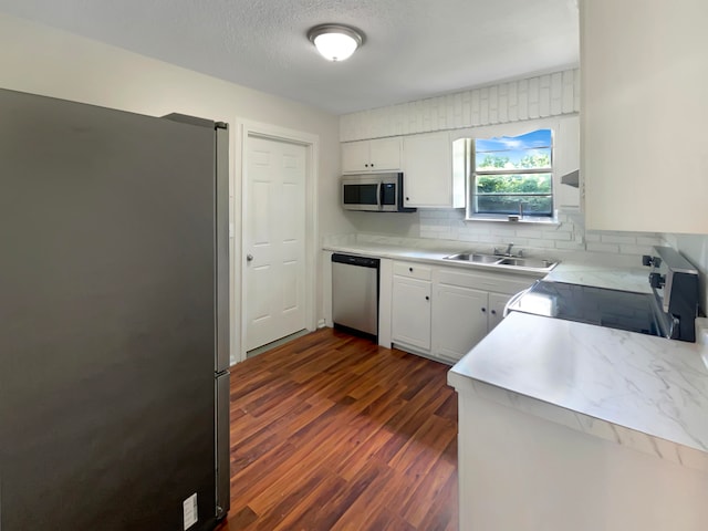 kitchen with appliances with stainless steel finishes, dark hardwood / wood-style floors, white cabinetry, and sink