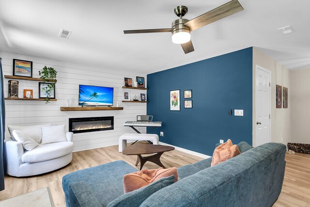 334 Water Oak Dr, Goose Creek, SC 29445 - living area featuring a glass covered fireplace, wood finished floors, a ceiling fan, baseboards, and an accent wall
