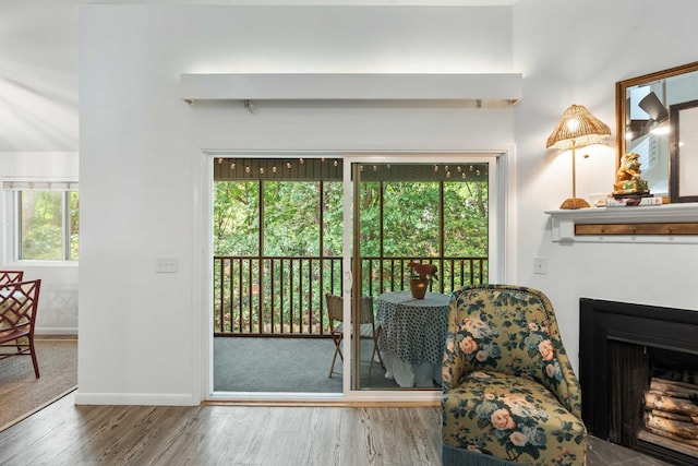 doorway to outside with wood finished floors, baseboards, and a fireplace