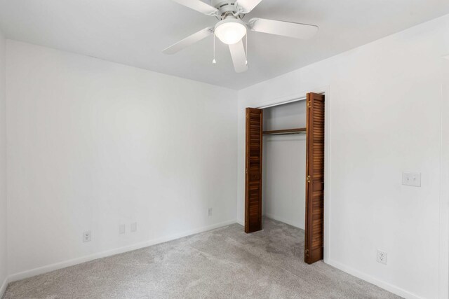 unfurnished bedroom featuring carpet, a closet, baseboards, and a ceiling fan