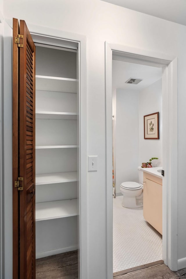 bathroom with toilet, vanity, and baseboards