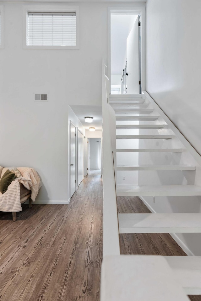 stairs with wood finished floors and a towering ceiling