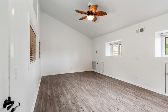 spare room with lofted ceiling, healthy amount of natural light, wood finished floors, baseboards, and a ceiling fan