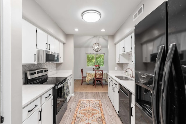 kitchen with appliances with stainless steel finishes, a sink, light wood-style flooring, light countertops, and tasteful backsplash
