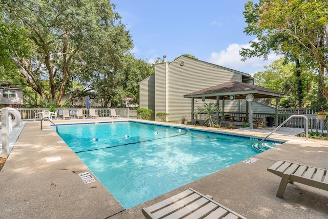 community pool with a gazebo, fence, and a patio