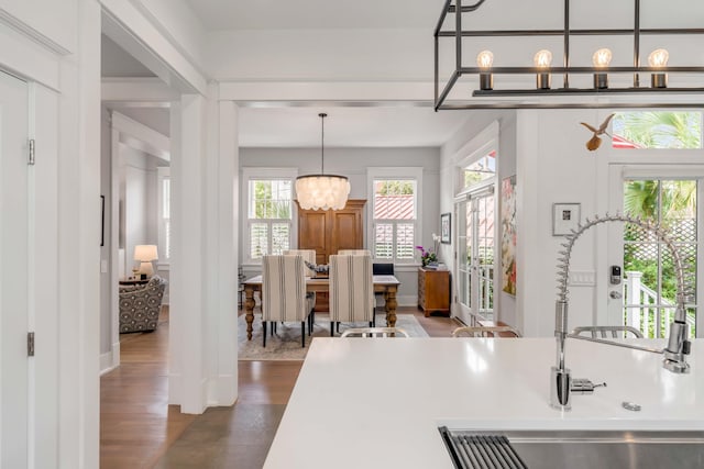 kitchen with a sink, decorative light fixtures, light countertops, a chandelier, and dark wood-style flooring