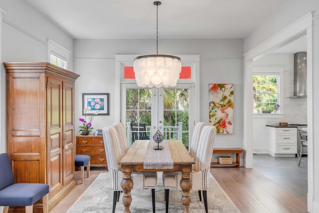 dining room with a notable chandelier, french doors, and light wood-type flooring