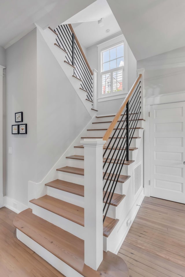 stairway featuring visible vents, baseboards, and wood finished floors