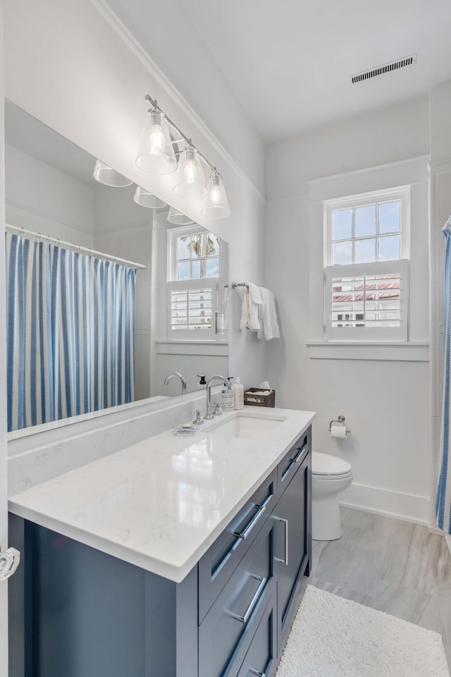 bathroom with vanity, visible vents, baseboards, curtained shower, and toilet