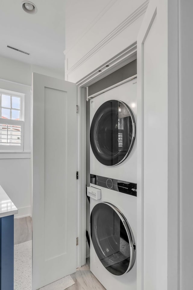 laundry room with laundry area, visible vents, and stacked washing maching and dryer