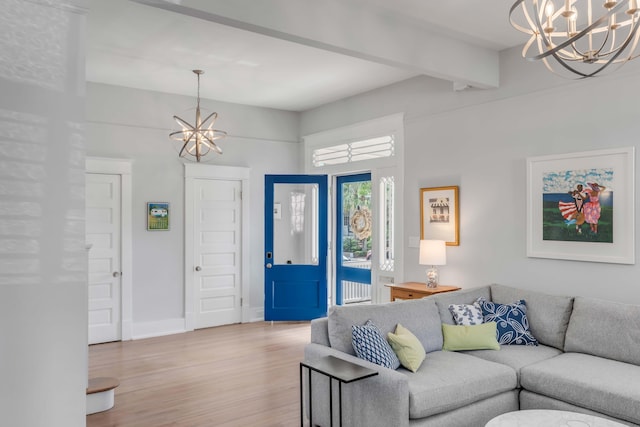 living room with an inviting chandelier, light wood-style floors, baseboards, and beam ceiling