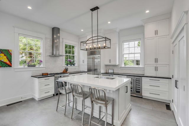 kitchen featuring a wealth of natural light, tasteful backsplash, high end appliances, and wall chimney exhaust hood