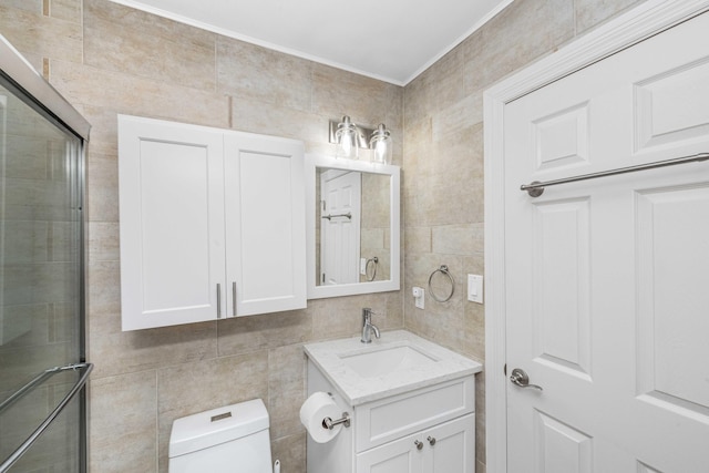 bathroom with vanity, toilet, tile walls, and a shower with shower door