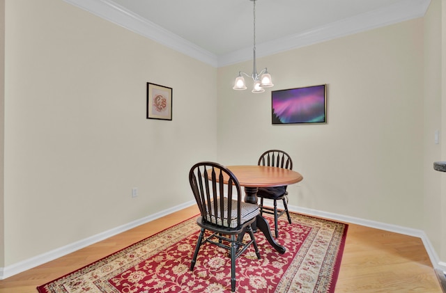 dining area featuring light wood-type flooring, a chandelier, and crown molding