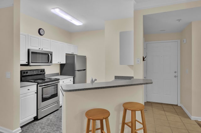 kitchen featuring white cabinetry, a breakfast bar, kitchen peninsula, appliances with stainless steel finishes, and light tile patterned floors