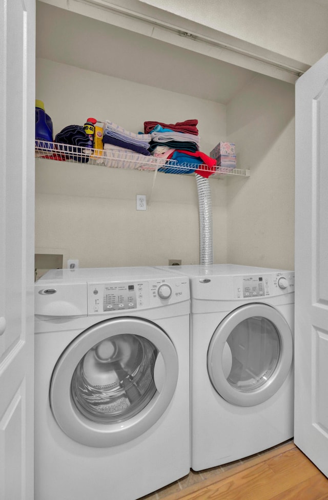 laundry room featuring separate washer and dryer and light hardwood / wood-style flooring