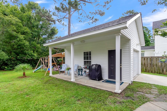 rear view of property with a playground, a patio, and a yard