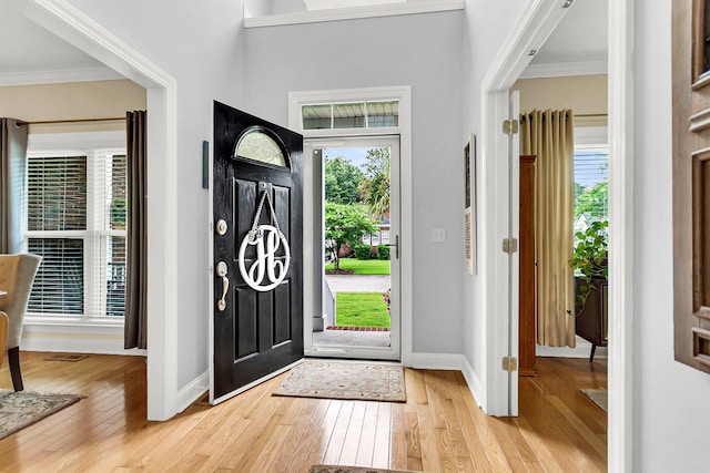 entrance foyer featuring crown molding and light wood-type flooring