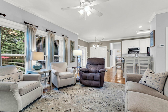 living room with crown molding, ceiling fan with notable chandelier, and light hardwood / wood-style floors