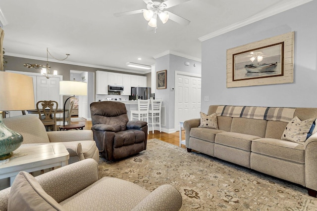 living room with ornamental molding, wood-type flooring, and ceiling fan