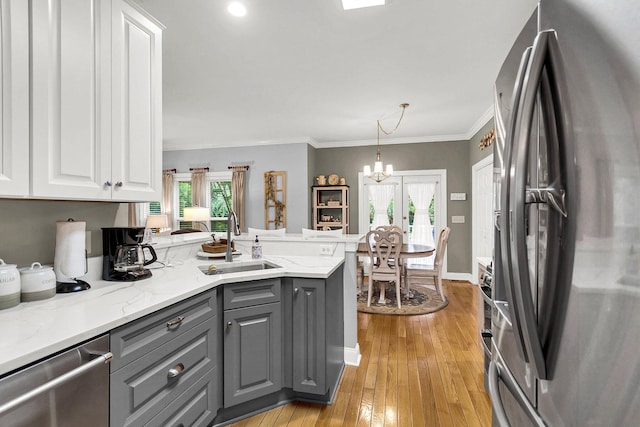 kitchen featuring decorative light fixtures, white cabinetry, sink, gray cabinetry, and stainless steel appliances