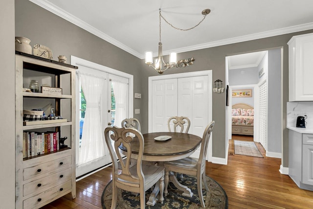 dining area with a notable chandelier, crown molding, and dark hardwood / wood-style floors