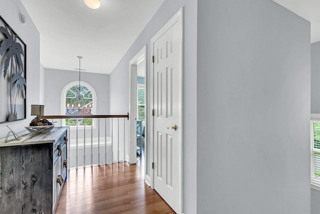 hallway with hardwood / wood-style flooring, lofted ceiling, and a chandelier