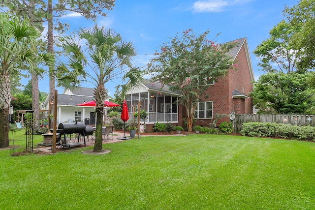 rear view of property featuring a sunroom, a patio area, and a lawn