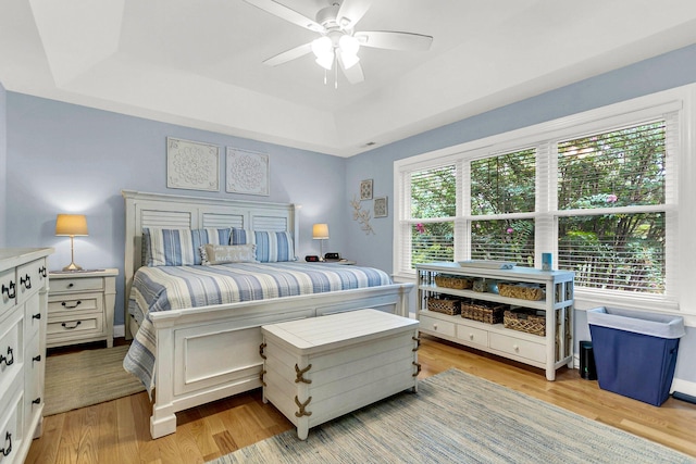 bedroom featuring a raised ceiling, ceiling fan, and multiple windows