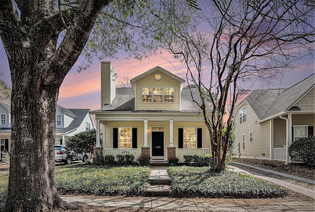 view of front of home featuring covered porch and a chimney